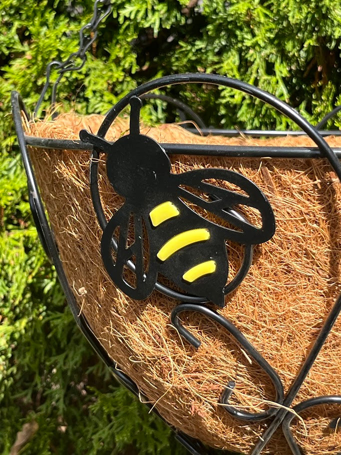 Decorative bee on a woven basket with greenery in the background