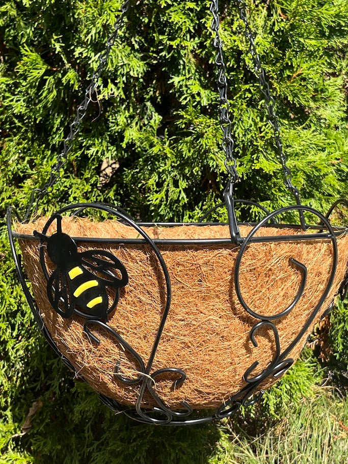 Wicker plant holder with a hanging chain against a green bush background