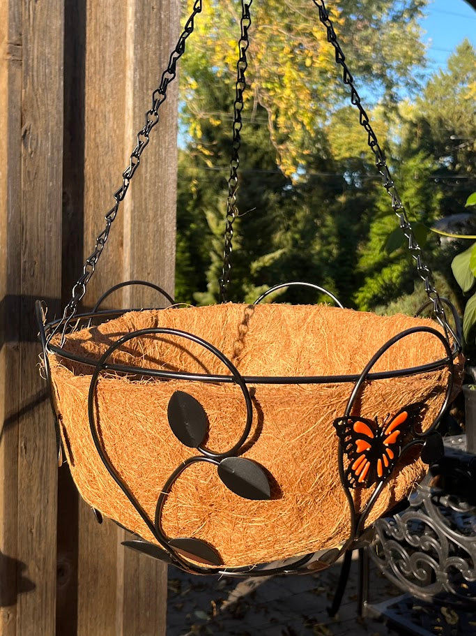 Decorative hanging basket with metal butterfly design against a natural background