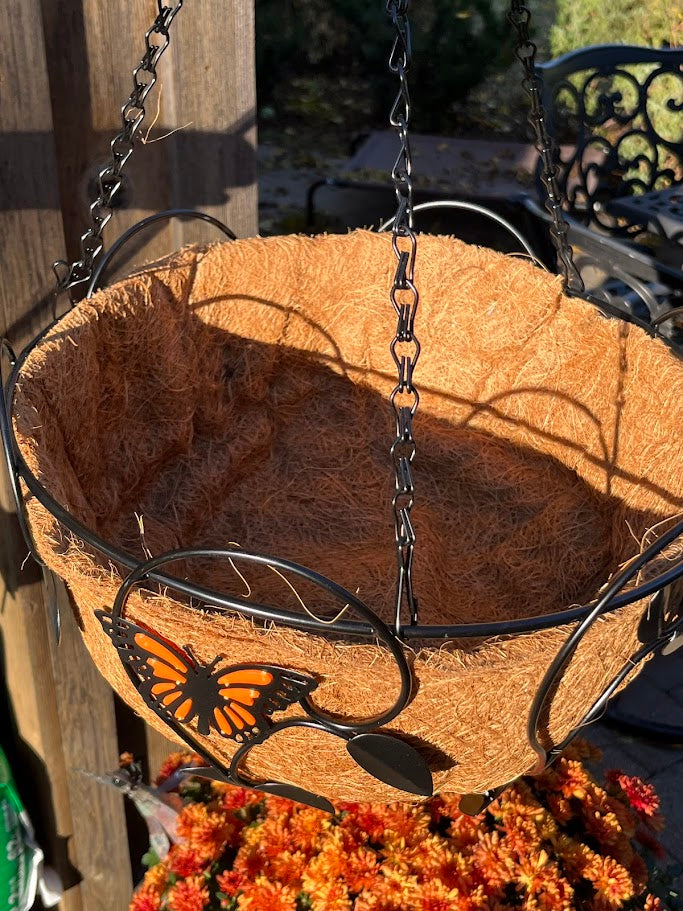 Coconut fiber hanging basket with metal butterfly design and flowers in front