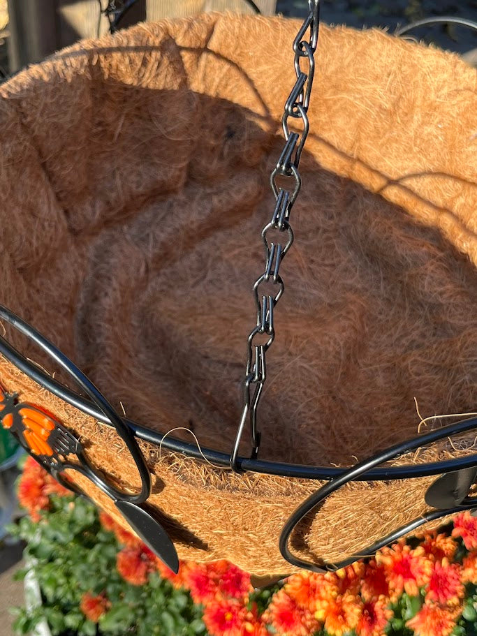 Coconut fiber hanging basket with metal chain and hooks against a floral background