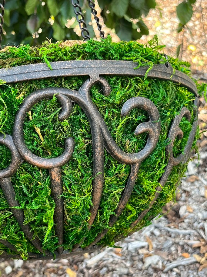 Decorative metal hanging planter with moss on a natural background