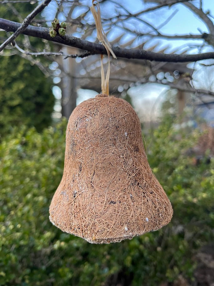 Coir bird feeder hanging from a branch with a natural background