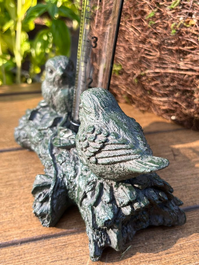 Decorative bird sculpture on a wooden surface with a plant in the background