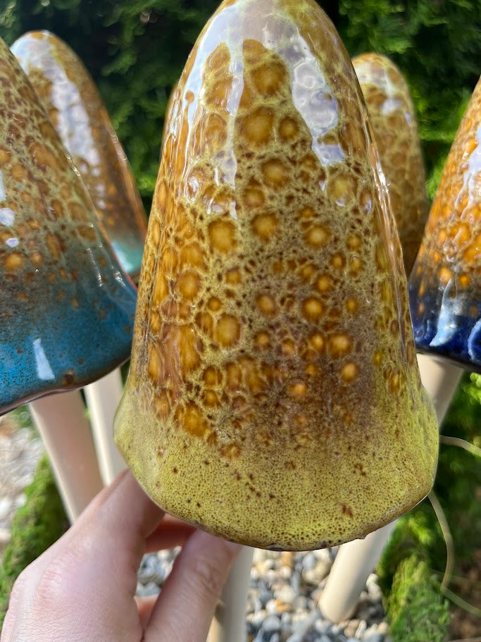 Hand holding a ceramic pot with textured surface outdoors
