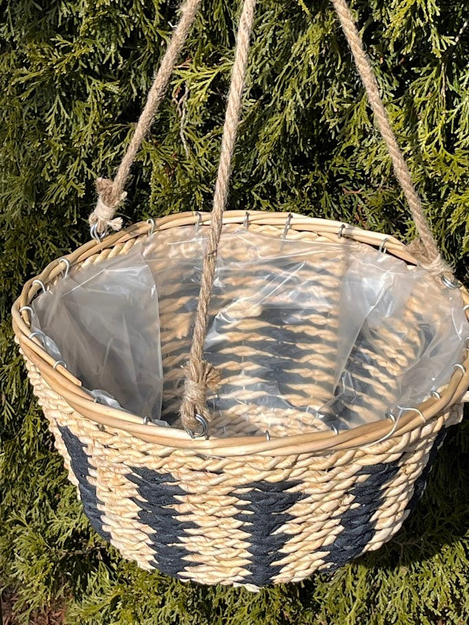 Woven basket with a clear plastic liner hanging against a green leafy background