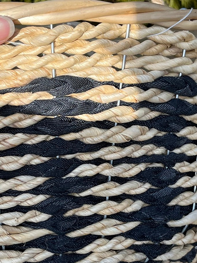 Close-up of braided black and beige rope with metal pins holding it together.