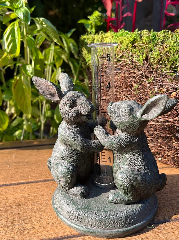 Decorative rain gauge with rabbit sculptures outdoors