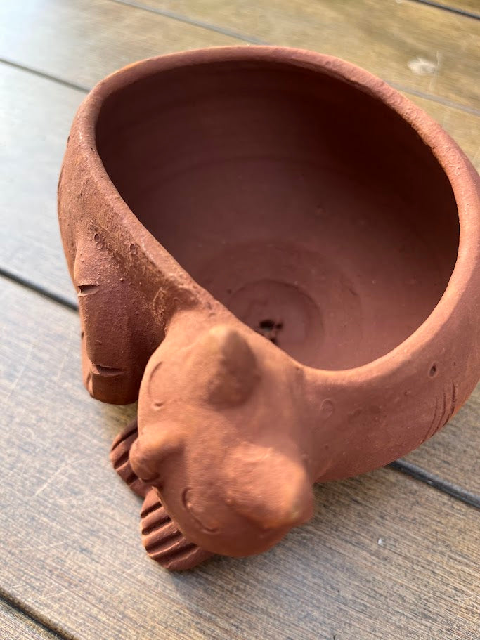 Terracotta pot shaped like a cat on a wooden surface