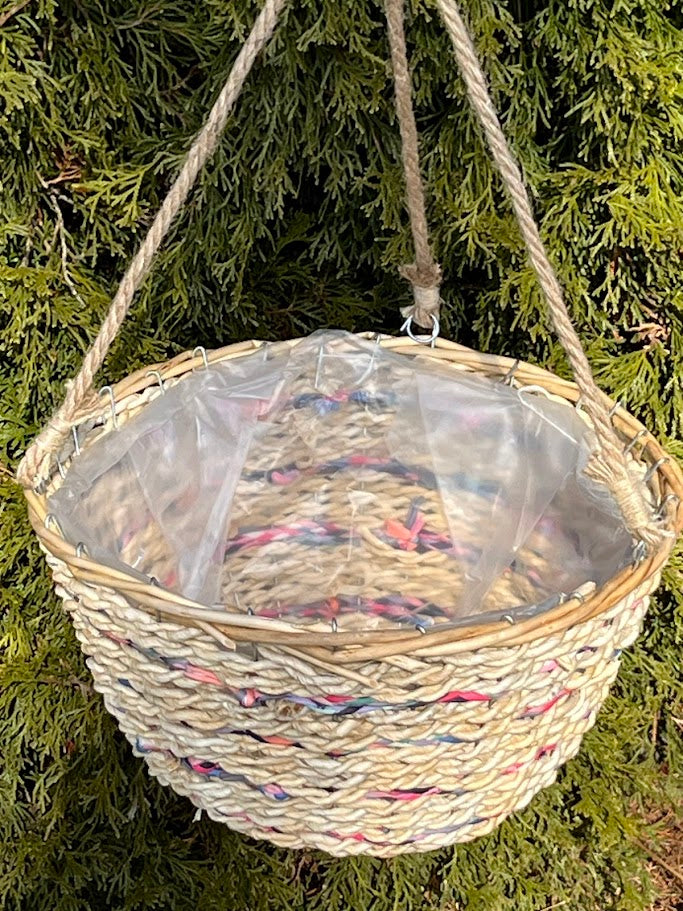 Woven hanging basket with colorful rope lining against a green foliage background