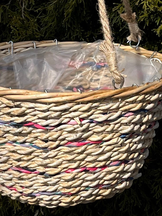 Woven basket with colorful threads hanging against a dark background