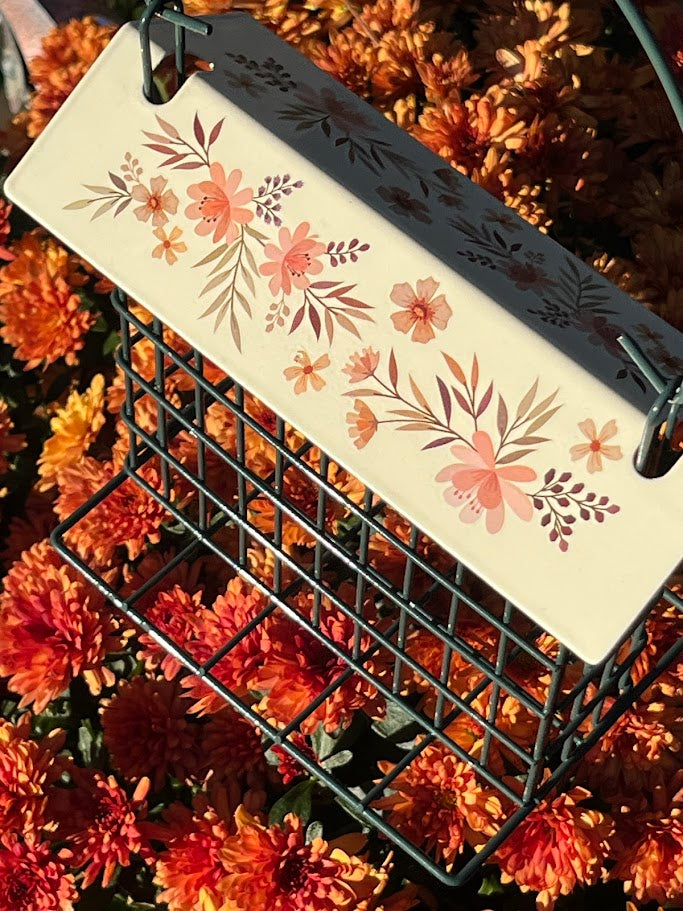 Floral-patterned product on a black metal stand surrounded by orange flowers