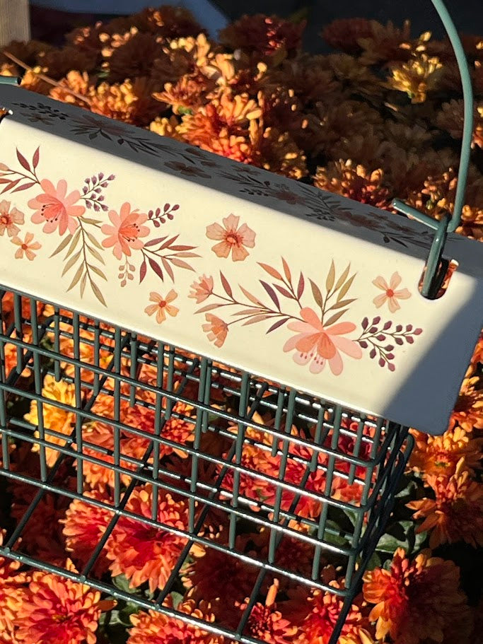 Decorative bird feeder with floral design on a background of orange flowers