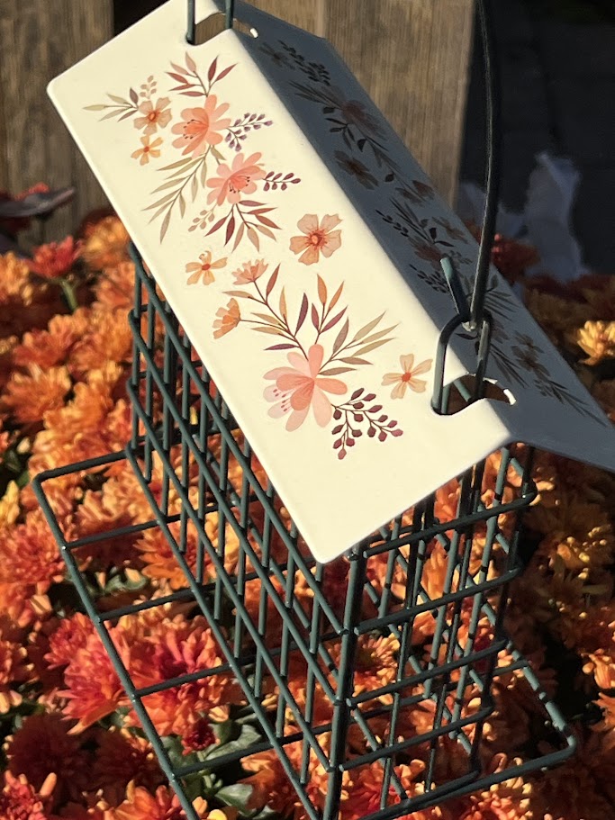 Decorative bird feeder with floral design on a background of orange flowers