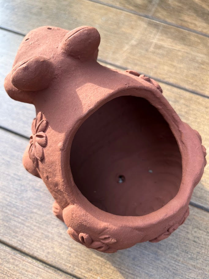 Terracotta pot shaped like a bear on a wooden surface