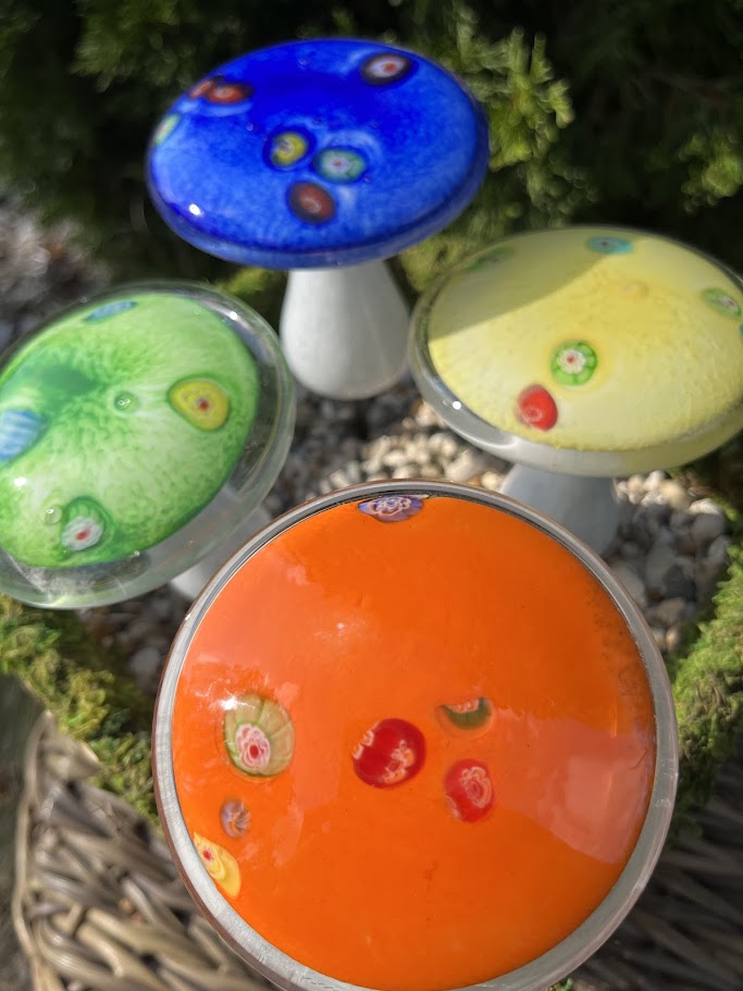 Colorful mushroom-shaped objects with different colored caps on a natural background.