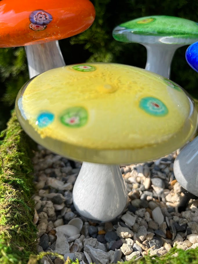 Decorative glass mushrooms with colorful tops on a natural background