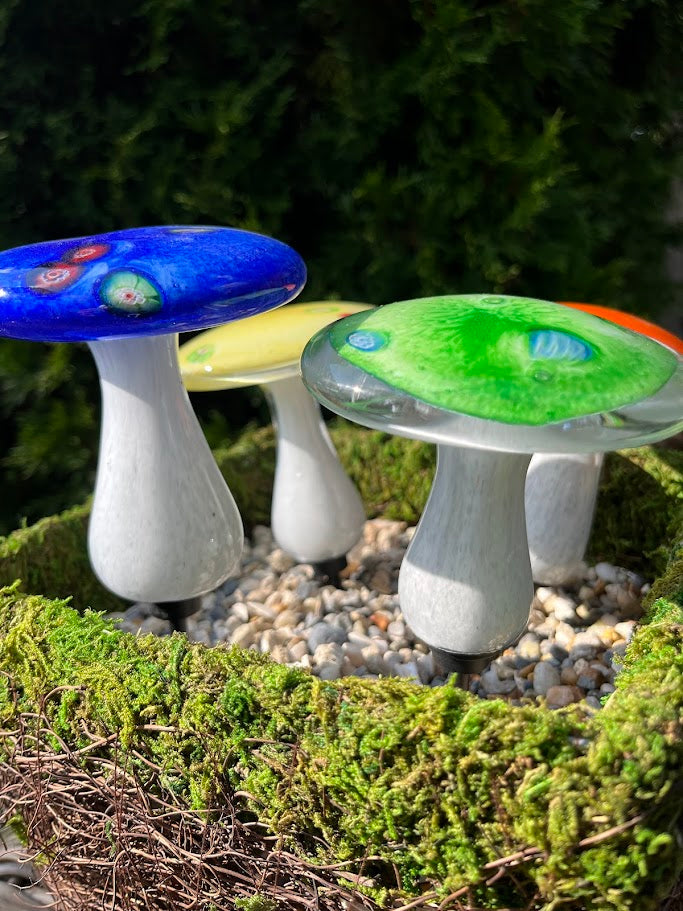 Colorful mushroom-shaped objects on a green mossy surface with a blurred natural background