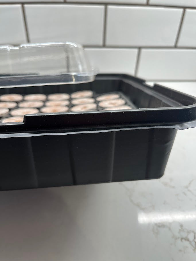 Black plastic tray with small round objects on a white surface