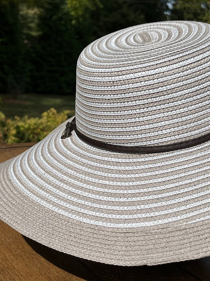 Wide-brimmed straw hat with a black band on a blurred natural background