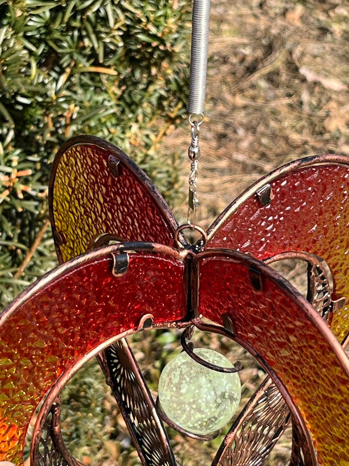 Decorative heart-shaped metal ornament hanging outdoors with greenery in the background