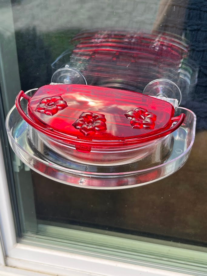 Red hummingbird feeder attached to a glass window