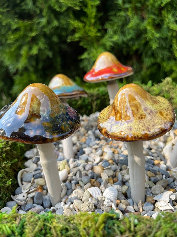 Colorful mushroom decorations on pebbles with a green foliage background