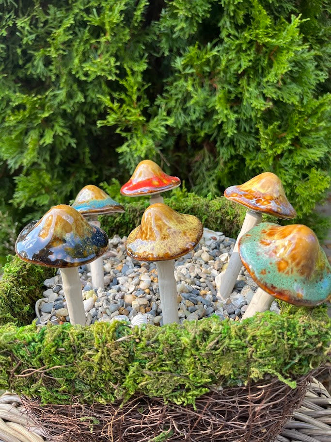 Colorful mushroom figurines on a bed of moss with a green bush background