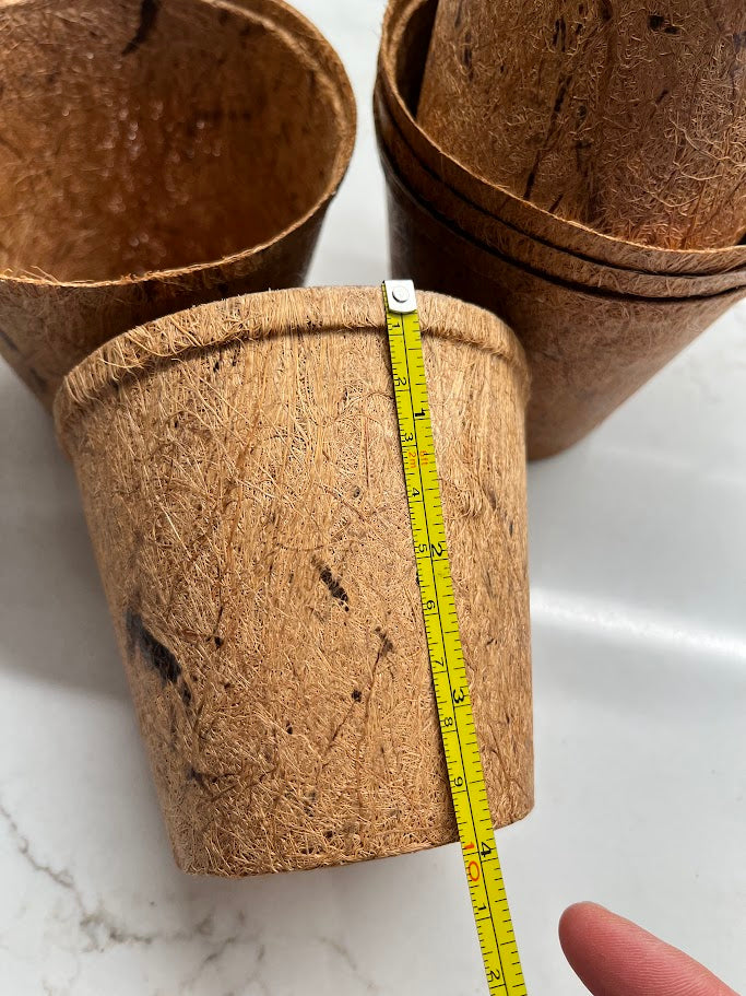 Three brown paper cups with a measuring tape on a white marble surface