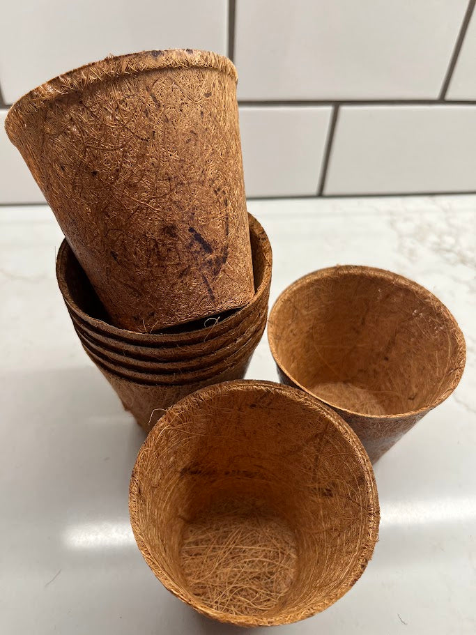 Stack of brown biodegradable cups on a white surface with a tiled wall background