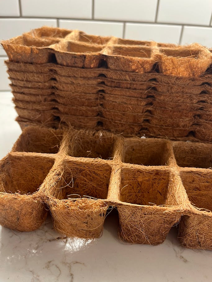 Stack of brown coir pots on a white surface with tiled wall background