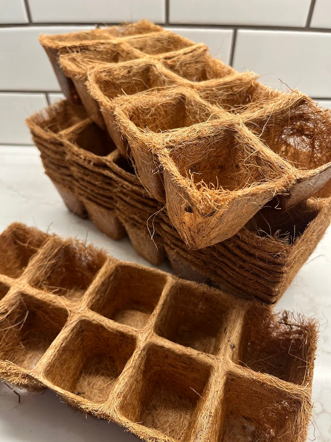 Stack of brown coir pots on a white surface with a tiled wall background