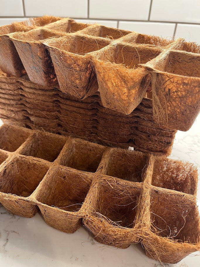 Stack of brown coconut coir pots on a white surface