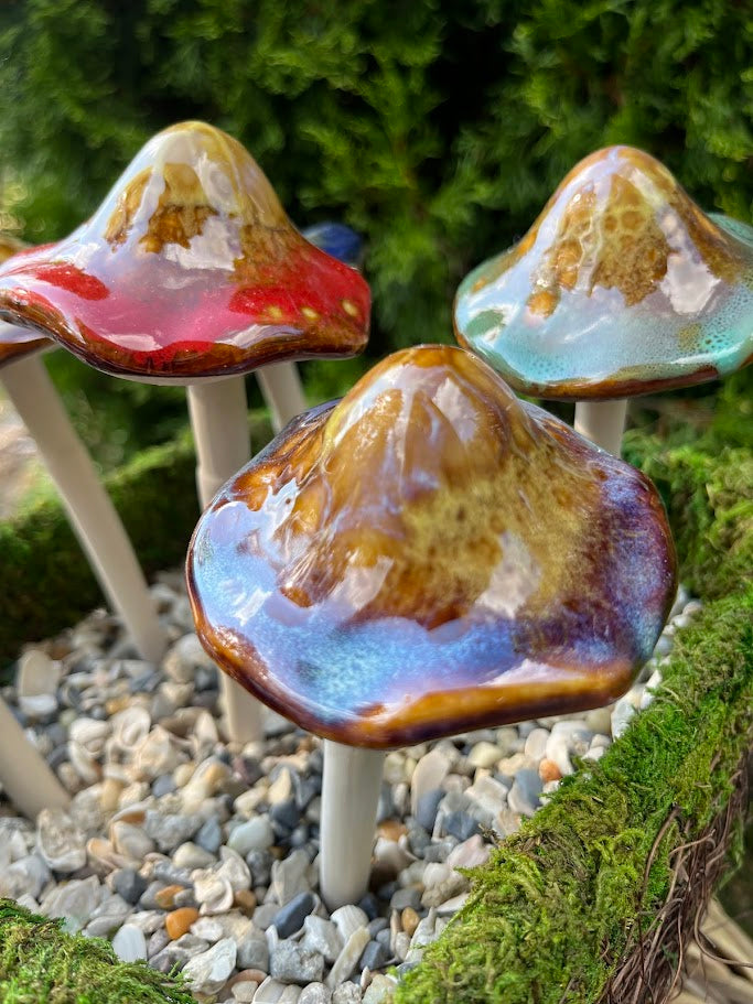 Colorful mushroom-shaped objects on sticks in a garden setting with greenery.