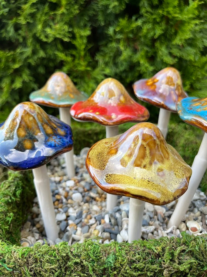 Colorful ceramic mushrooms on a garden path with greenery in the background