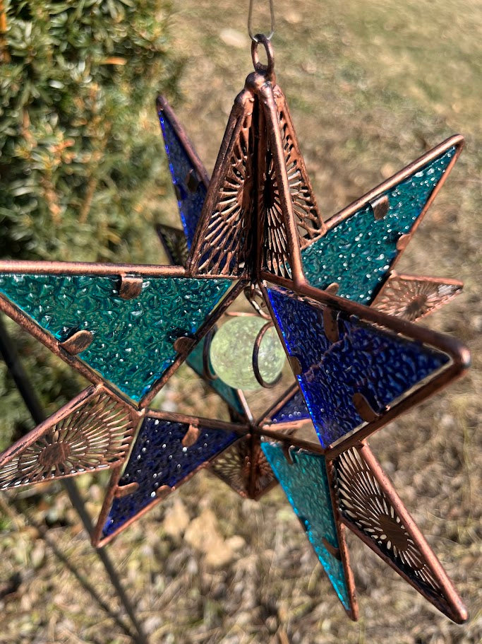 Decorative star ornament with blue and green colors on a natural background