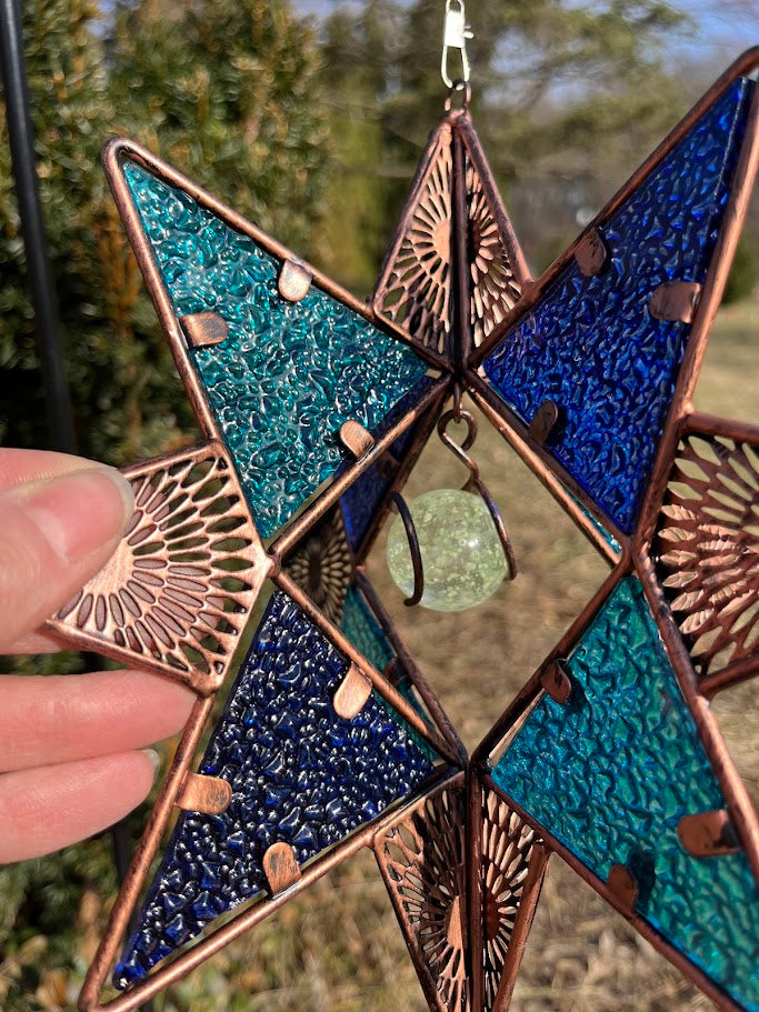 Decorative star ornament with blue and green colors on a natural background