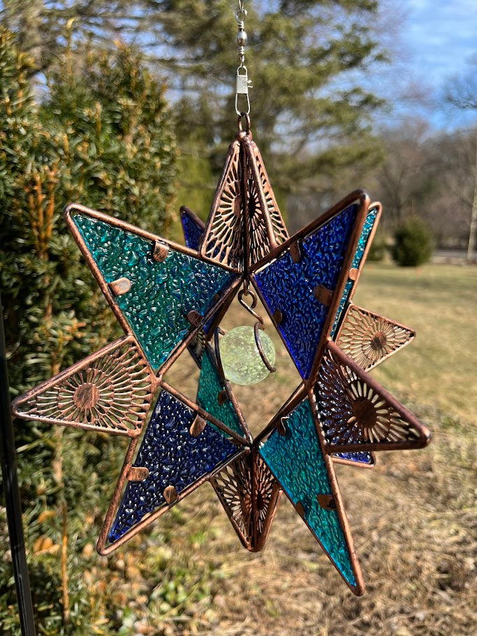 Decorative star ornament with blue and green colors on a natural background
