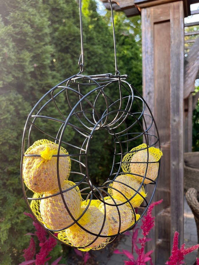 Decorative wreath with yellow balls hanging from a wire frame against a natural background.